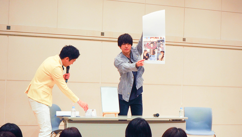ファン投票による「みんなで選ぶカレンダー投票」のコーナーで、参加者に見えるように写真を指し示す遊馬晃祐さん